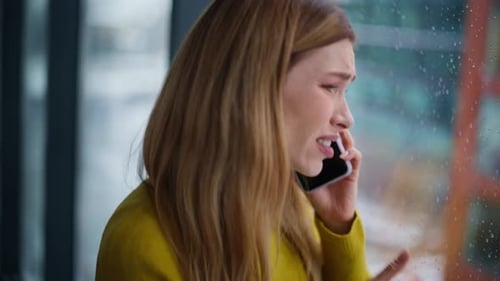 Sad Woman Talking on Phone by Window