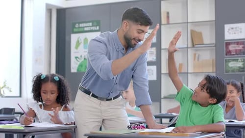 Teacher assists biracial boy and girl in a classroom at school