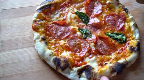 Cutting Slice of Delicious Pepperoni Pizza with Basil