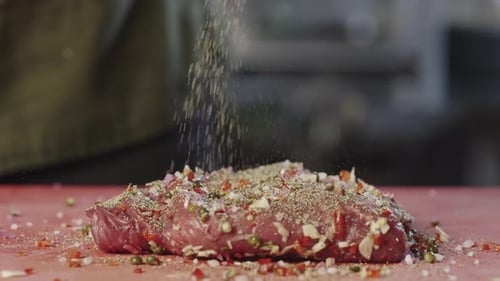The Cook Sprinkles Raw Meat with Ground Black Pepper