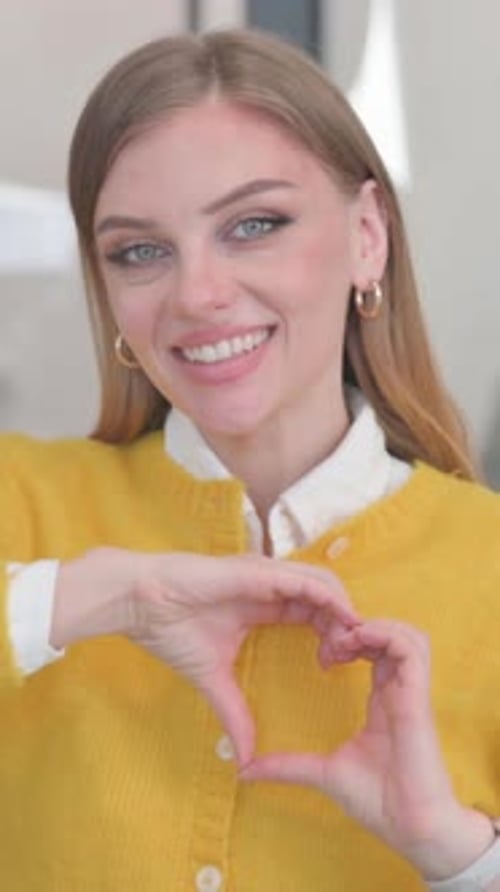 Smiling Woman Makes Heart Shape with Hands