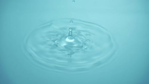 Water Drop Impact Creates Ripples on Blue Surface
