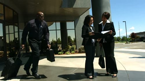 Business People Arriving at Building with Luggage