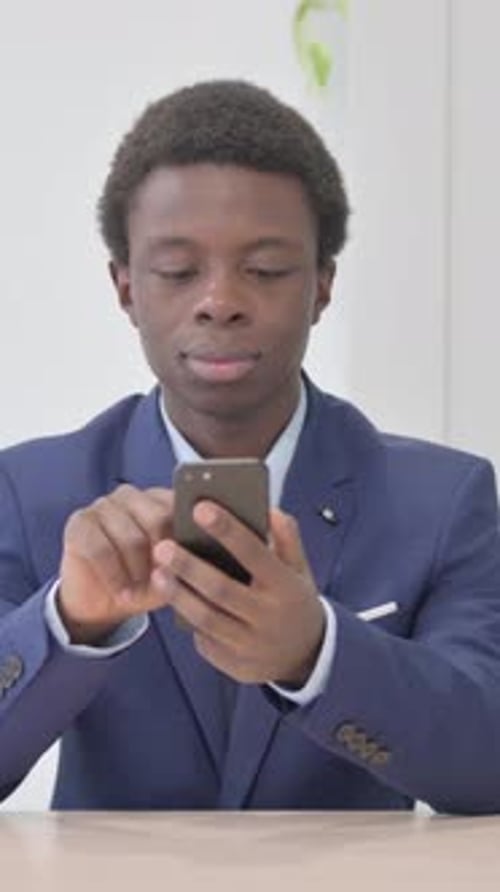 Young African Businessman Browsing Internet on Smartphone in Office, Vertical Video