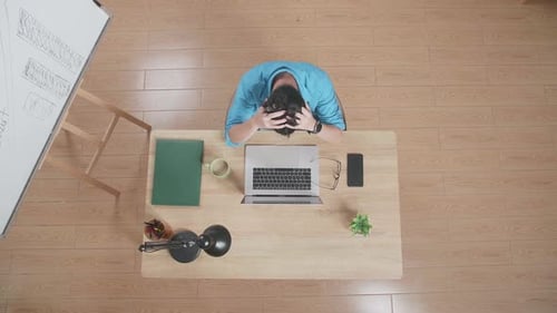 Top View Of A Tired Man Having A Headache Typing On A Laptop At Home