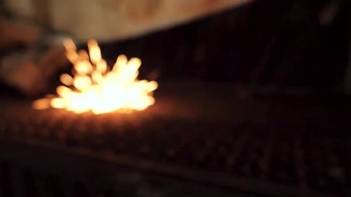 Beim Schweißen prallen Funken in Zeitlupe vom Metallgitterboden ab.