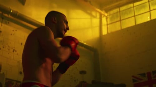 Muscular Man Boxing in Warm-Lit Urban Gym