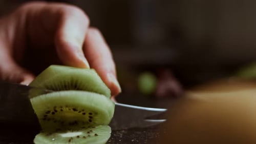 Slicing a Juicy Green Kiwi on a Cutting Board Macro View
