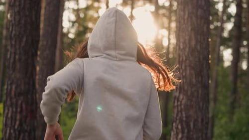 Woman in Hood Jogging in Forest