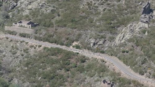 Flug mit einer Drohne, die eine Bergstraße visualisiert und bergab zirkuliert, sind eine Gruppe von Radfahrern in