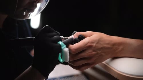 Manicurist Buffing Client's Nails with Rotary Tool