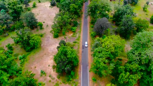 Aerial view of a car riding on the highway through the forest on the countryside. Cinematic drone fo