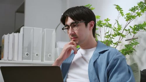 Young caucasian man planning project or using artificial intelligence on laptop in home office.