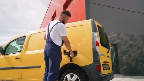 Delivery Man Charging Electric Van at Station