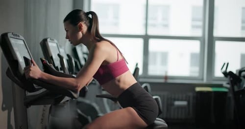 A Young Beautiful Brunette Girl in Sportswear Exercises on a Simulator in the Gym Doing Cardio