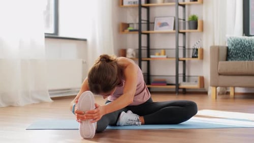 Woman on yoga mat stretching leg indoors daytime