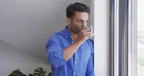 Handsome Man Drinking Coffee by a Window