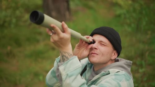 Un explorateur regarde à travers des jumelles une personne appréciant une vue rapprochée de la faune en plein jour, un homme dans un pré