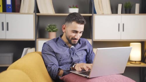 Young man using laptop, texting.