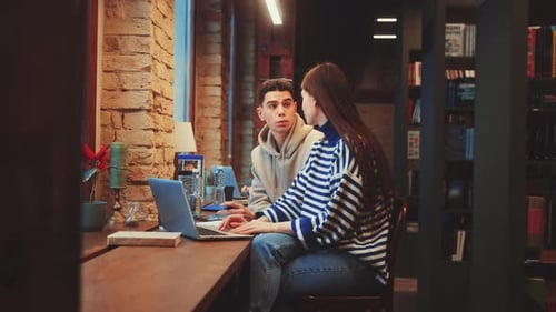 Studierende arbeiten an den Schreibtischen der Bibliothek zusammen