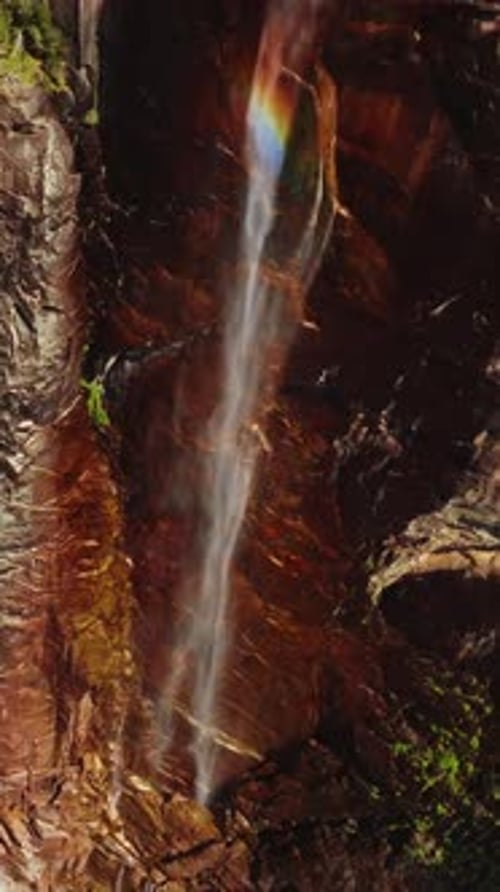 Rainbow appearing in the stream falling from huge cliff.