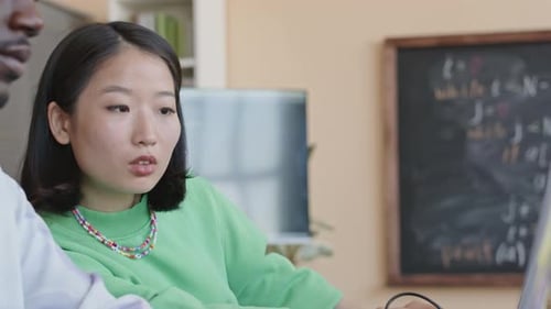 Asiatisches Mädchen bittet Gruppenmitglied um Hilfe bei der Programmierstunde