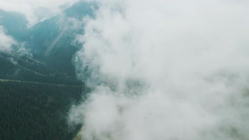 Aerial Camera Flight Through Clouds Above Forest and Mountains