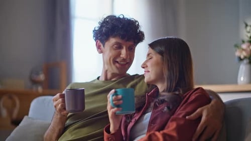 Smiling Couple Enjoying Coffee Together on Couch