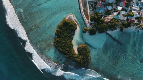 green island with white sand beach waves and blue lagoon