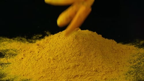 Pieces Of Peeled Turmeric Rhizomes Dropping Into Heap Of Turmeric Powder. slowmo