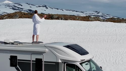 Funny Tourist in Bathrobe Staying on a Roof of His Motorhome and Exciting the View