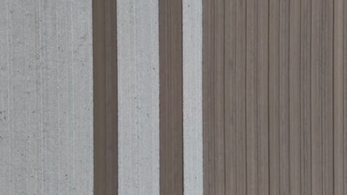 Overhead drone shot of alternating pale and dark furrows stretching across tilled field