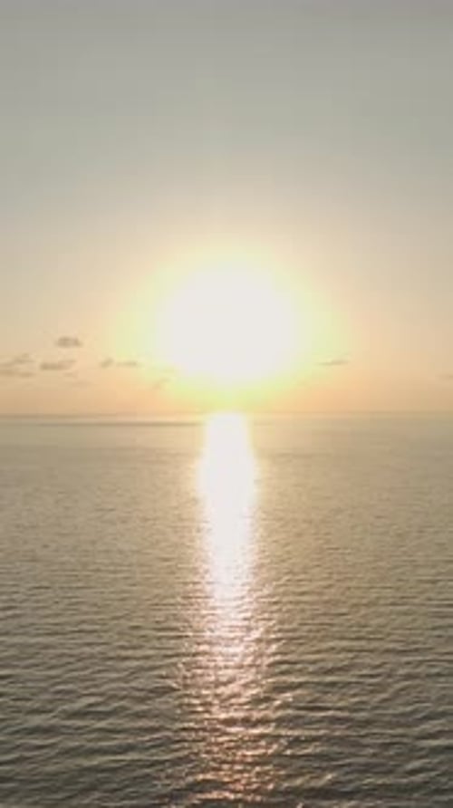 Vidéo verticale : vue aérienne des textures de l'océan alors que le coucher du soleil projette des teintes chaudes sur les ondulations calmes