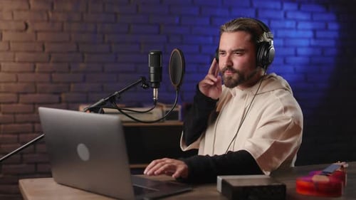 Man Speaking at Microphone in Studio With Laptop