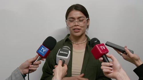 Young Woman Giving Interview to Reporters with Microphones