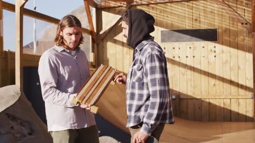 Video of diverse male skateboarders talking in skate park