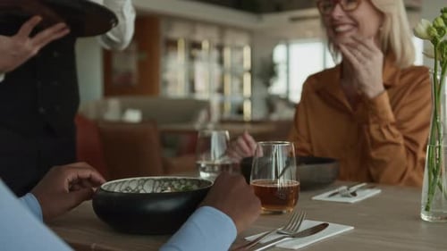 Server Bringing Wine Glasses to Guests in Restaurant