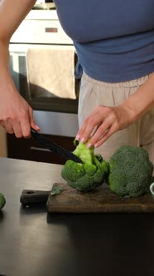 Cutting Fresh Broccoli On A Wooden Board In A Kitchen