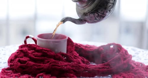 Teapot Pours Hot Tea into Mug with Scarf