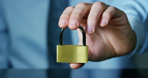A businessman in shirt and tie shows a padlock with keys as a sign of security.The padlock symbol