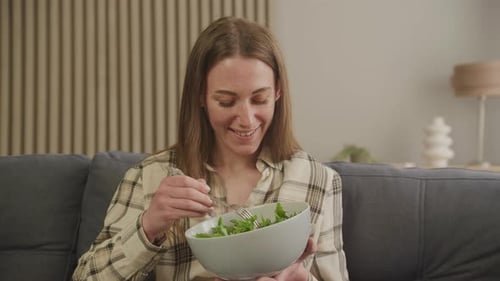 Woman Eats Salad on Couch at Home