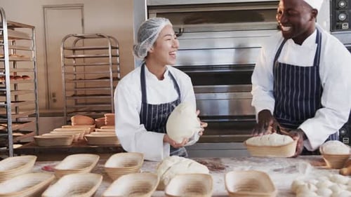 Happy diverse bakers working in bakery kitchen, kneading dough for bread in slow motion
