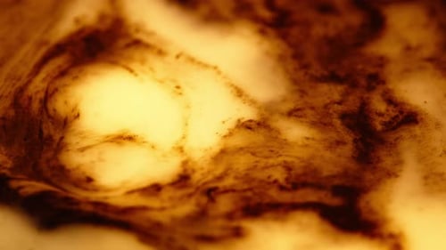 Braune und gelbe Acrylfarbe, die in Flüssigkeit wirbelt