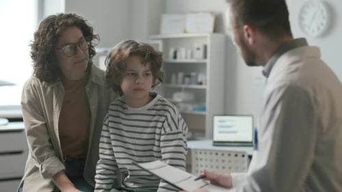 Mother and Child Talking to Doctor during Medical Consultation in Clinic