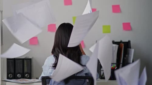 Frustrated Woman Throwing Papers in Office