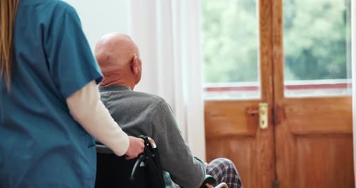 Woman pushes Senior in Wheelchair at Hospital