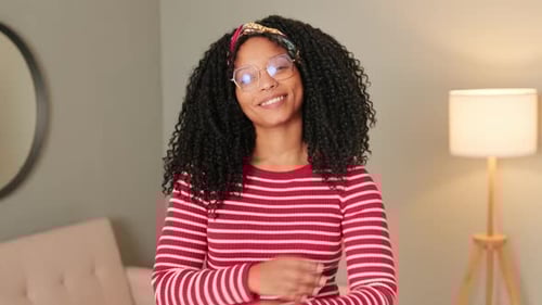Smiling woman standing in the living room looking at the camera crossing her arms