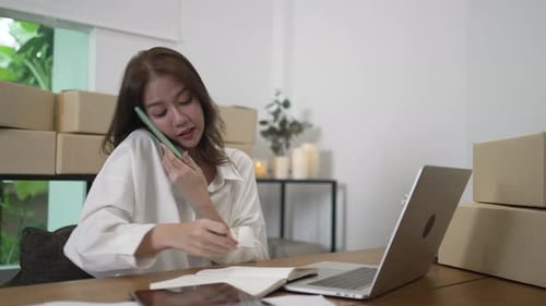Woman Working on Laptop and Talking on Phone