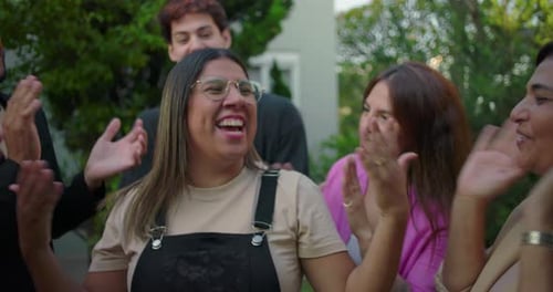 Latina woman smiling with excitement and playfully asking for more applause as friends cheer her