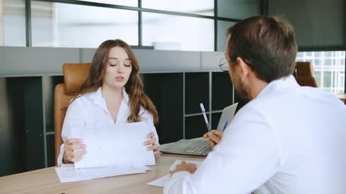 Professional Discussion Occurs in a Modern Office Setting Where a Young Woman Presents Important